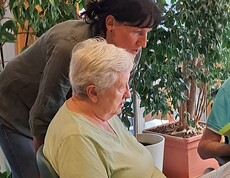 Eine Bewohnerin des Pflegewohnhauses nimmt im Rahmen des Tags der Demenz an einem gemeinsamen Singangebot teil, begleitet von einer Mitarbeiterin.