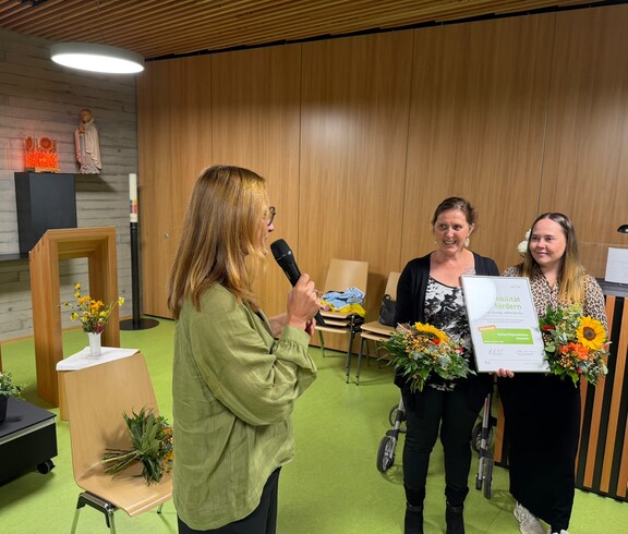 Bei der Verleihung des Gütesiegels „Mobilität im Alter“ präsentieren zwei Mitarbeiterinnen des Pflegewohnhauses Neumarkt gemeinsam mit einer Vertreterin von Styria vitalis die Auszeichnung und Blumensträuße.