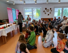 Bewohner*innen und Kinder nehmen gemeinsam an einer Osterandacht im Gemeinschaftsraum teil.
