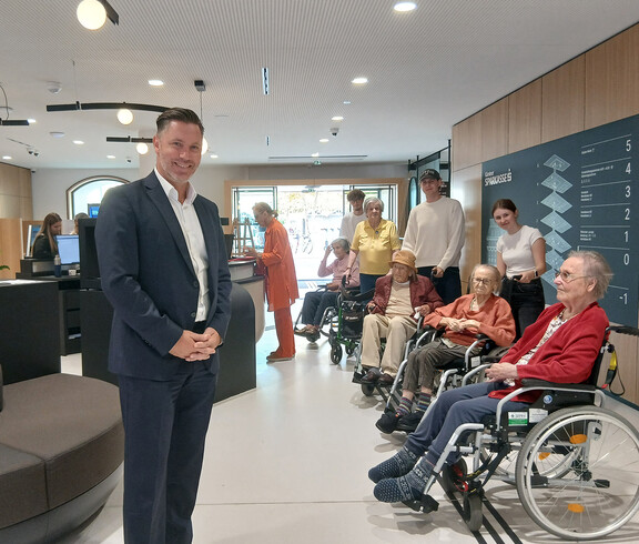 Senior*innen mit Betreuer*innen treffen sich mit einem Sparkassenmitarbeiter in der Filiale.