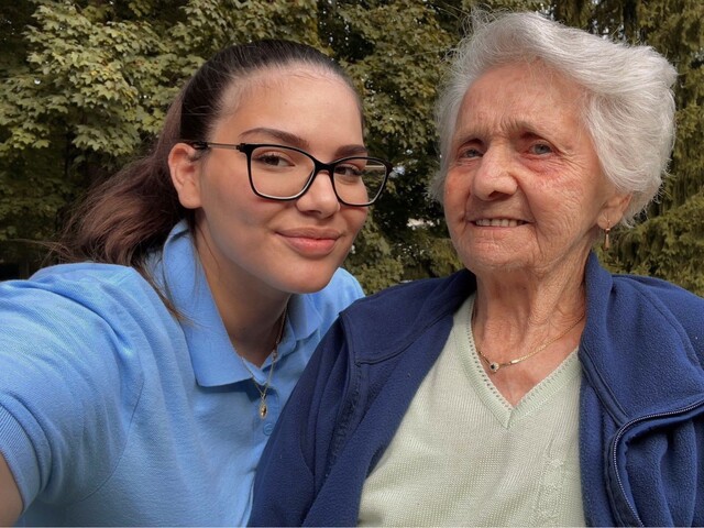 Zwei Frauen gehen in einem Gewölbegang, die jüngere hat der älteren den Arm um ihre Schulter gelegt.