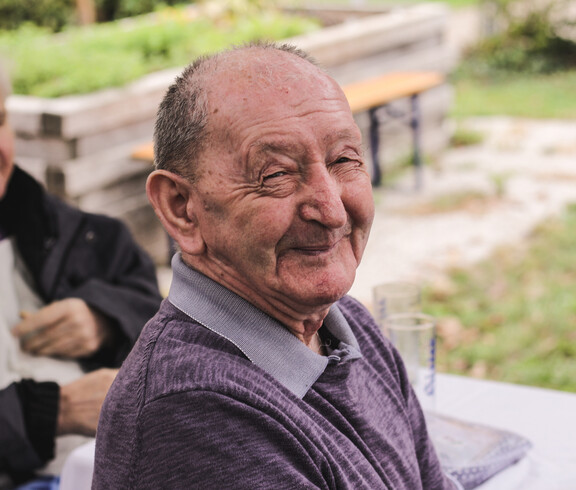 Bewohner des Caritas St. Hemma-Hauses sitzt beim Herbstfest im Garten.