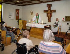 Zwei Pfarrer halten in der hauseigenen Kapelle eine Messe für die Bewohner*innen.