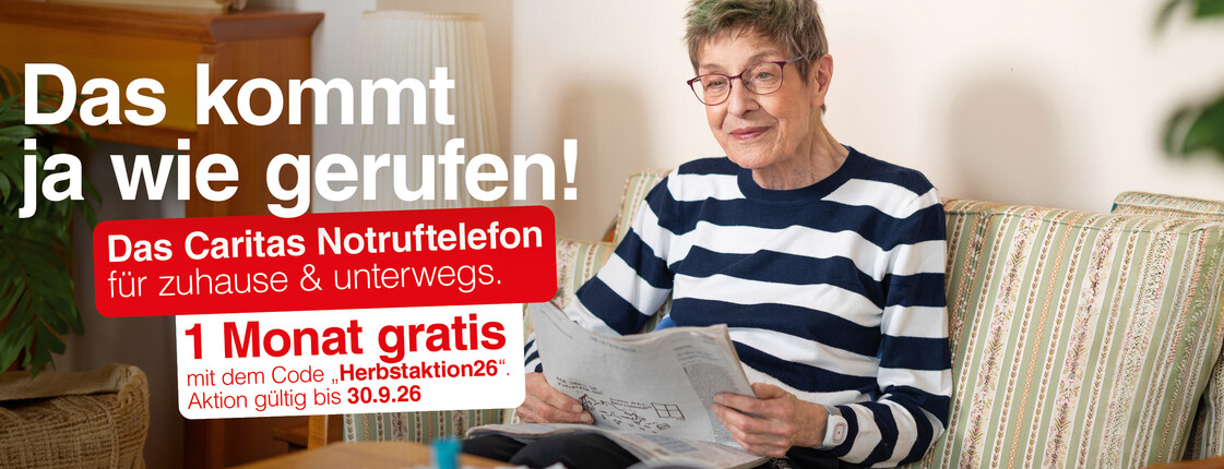 Ältere Person sitzt auf einem Sofa im Wohnzimmer und liest eine Zeitung. Links im Bild Werbetext: „Das kommt ja wie gerufen! Das Caritas Notruftelefon für zuhause & unterwegs. 1 Monat gratis! Aktion gültig bis 30.0.2026“.
