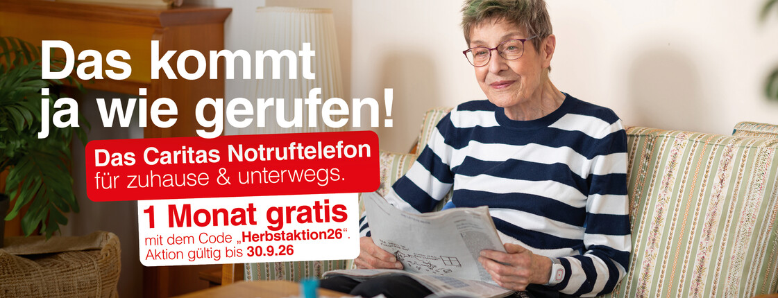 Ältere Person sitzt auf einem Sofa im Wohnzimmer und liest eine Zeitung. Links im Bild Werbetext: „Das kommt ja wie gerufen! Das Caritas Notruftelefon für zuhause & unterwegs. 1 Monat gratis! Aktion gültig bis 30.0.2026“.