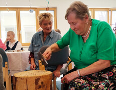 Bewohnerin schlägt mit Hammer im Spiel „Triff den Nagel“ einen Nagel in einen Holzblock ein.