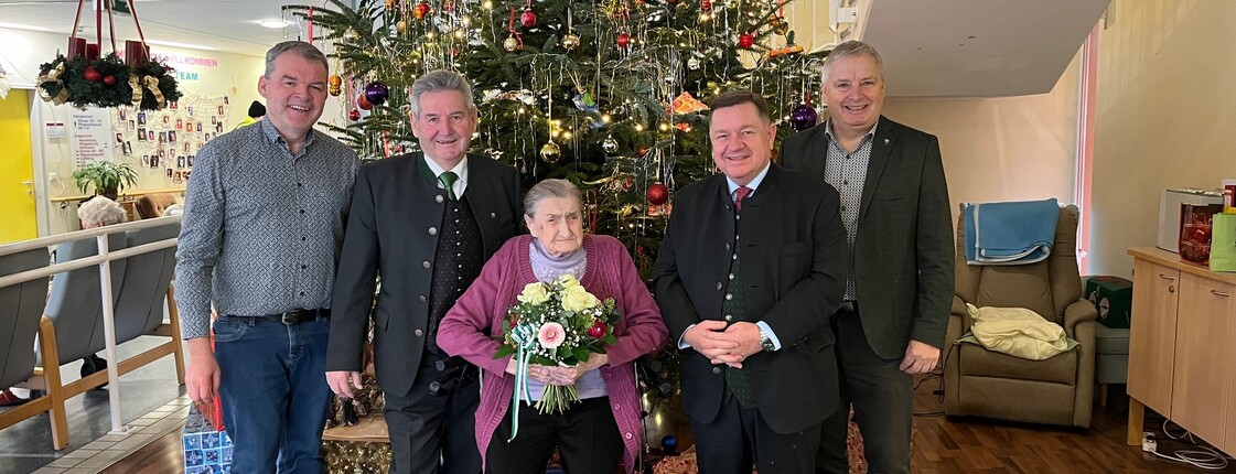 Hausleiter Josef Url, Bürgermeister ÖkR Josef Niggas, Vizebürgermeister Robert Sauer und BPO 2. Landtagspräsident Werner Amon, MBA, stehen nebeneinander und posieren für ein Gruppenfoto. In der Mitte steht Frau Markl, die einen Blumenstrauß in den Händen hält. Hinter der Gruppe ist ein festlich geschmückter Christbaum zu sehen. Die Personen blicken freundlich in die Kamera und stehen in einem offiziellen oder feierlichen Rahmen zusammen. 