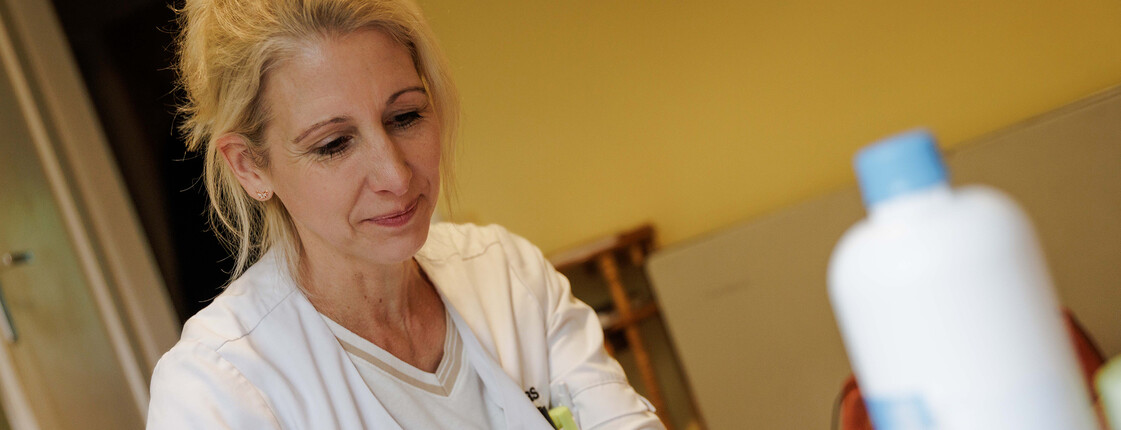 Eine Diplomierte Gesundheits- und Kranenpflegerin schneidet einen Verband zurecht. Vor ihr stehen Verbandsmaterialien.