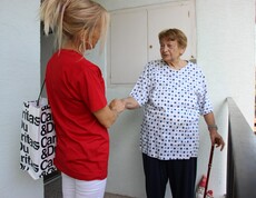 Caritas Mitarbeiterin der Hauskrankenpflege begrüßt Klientin zuhause