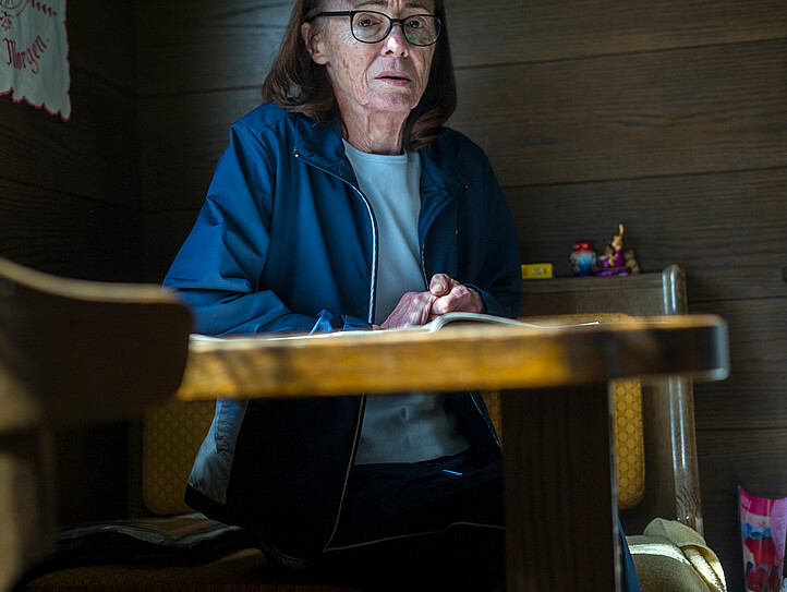 Eine Frau mit Brille sitzt an einem Küchentisch
