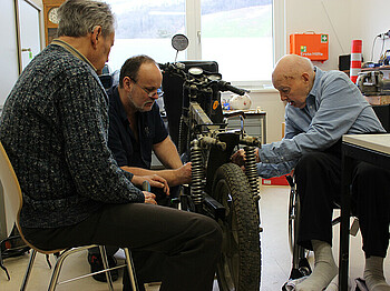 Tagesgast Otmar Schober, Haustechniker Georg Ponzer und Bewohner Fritz Brandl werkeln am Motorrad in der Werkstatt