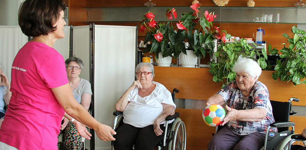 Seniorenanimateurin spielt mit BewohnerInnen mit Ball Caritas Haus St. Nikolaus in Neusiedl am See