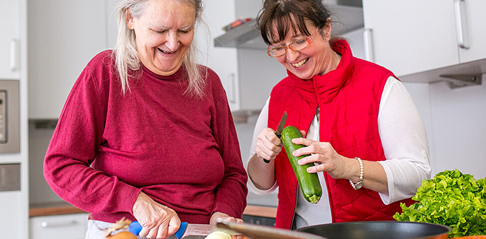 Eine alte Frau und eine Betreuerin beim Kochen in der Caritas Altenpension.