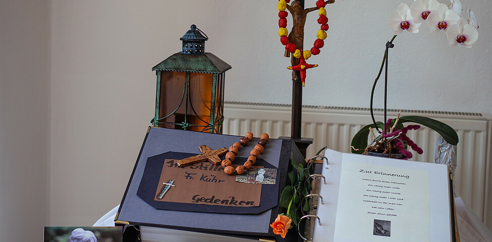 Traueraltar mit Verabschiedungsbuch, Christuskreuz, 2 Engel, Engel-Postkarte, Grablaterne und einer Blume.