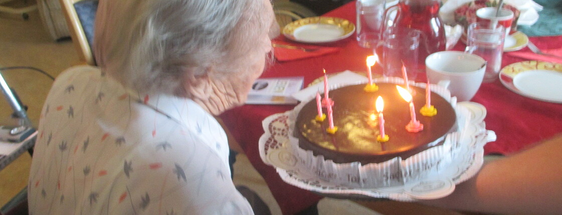 Bewohnerin Frau E beim Auspusten der Kerze auf der Geburtstagstorte