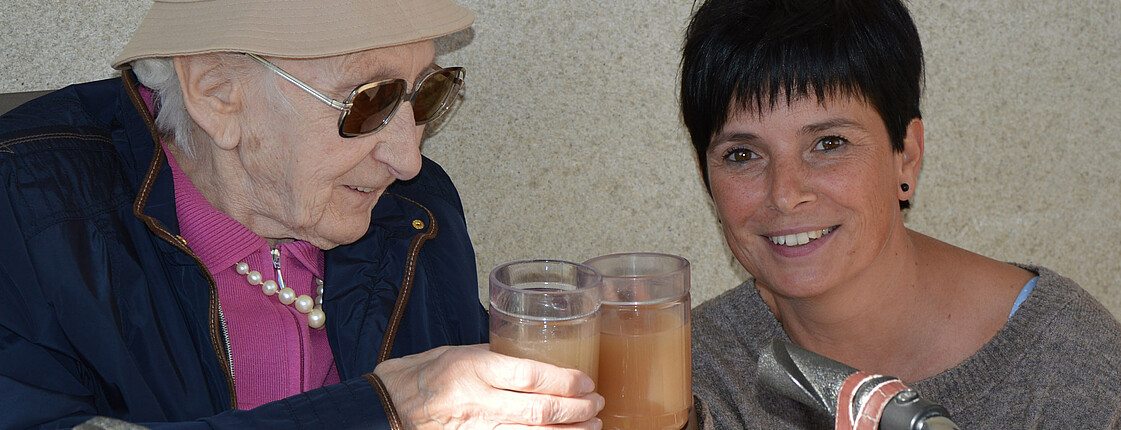 Eine Bewohnerin aus dem Caritas Haus Elisabeth trinkt Sturm mit Sandra Unger, der Hausleiterin.