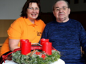 Eine Frau und ein Mann sitzen beim Adventkranz