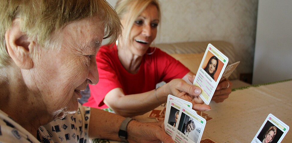 Caritas Mitarbeiterin der Hauskrankenpflege spielt mit Klientin Karten
