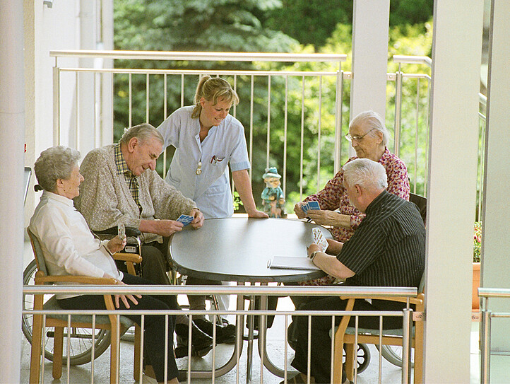 Ältere Personen beim Kartenspielen in einer betreuten Caritas Einrichtung